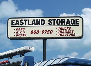 Eastland Crane storage sign above their 20 acre fenced storage lot showing they offer storage for cars, RV's, boats, trucks, trailers, tractors.